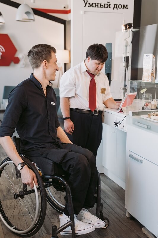 Image showing a man in a wheelchair discussing workplace accommodations with his co-worker under the Fair Employment and Housing Act (FEHA)