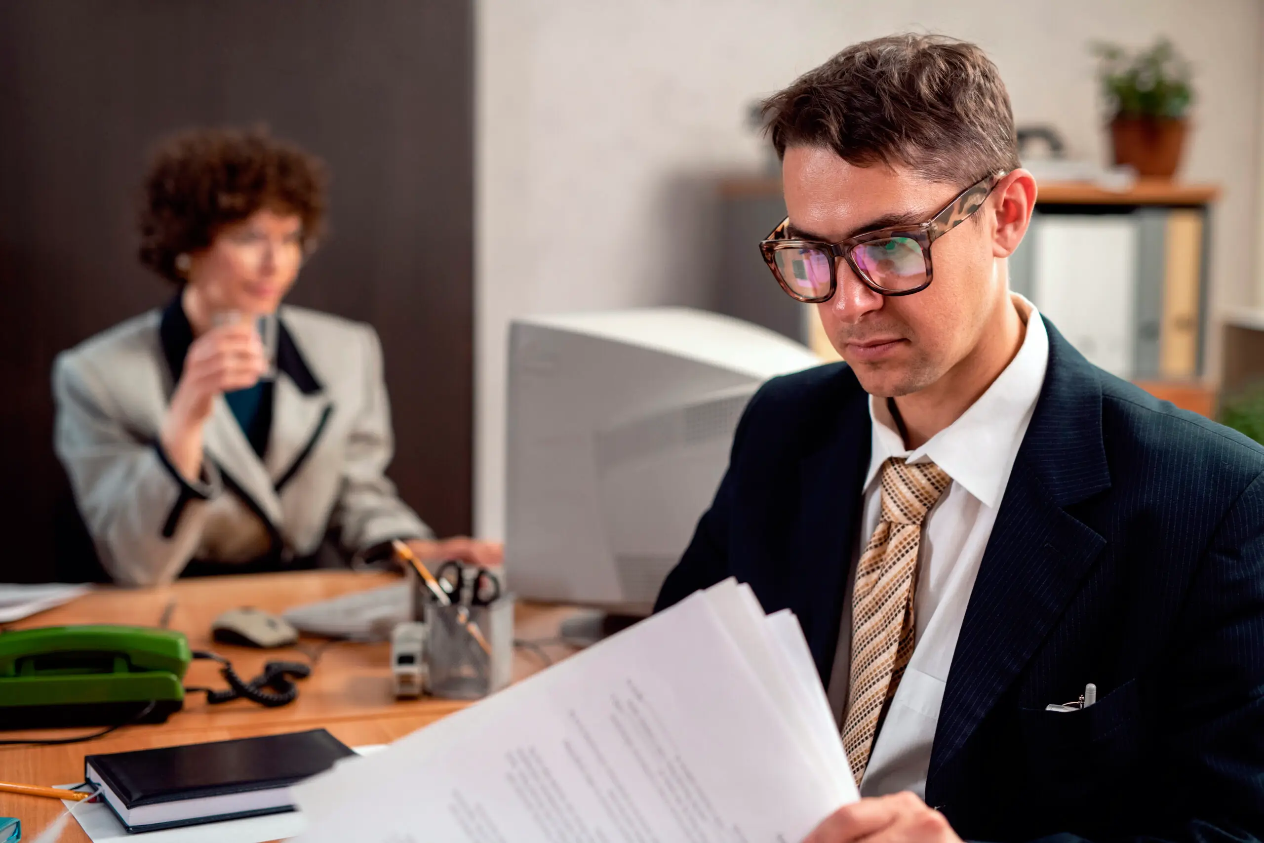 Male attorney reviewing papers; female employee consulting